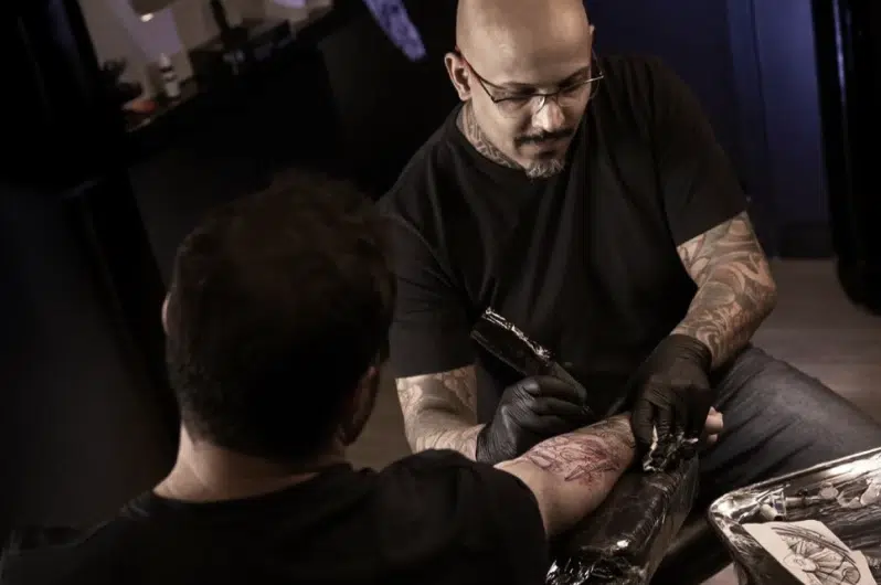 André Cojack executando a tatuagem no antebraço de um cliente