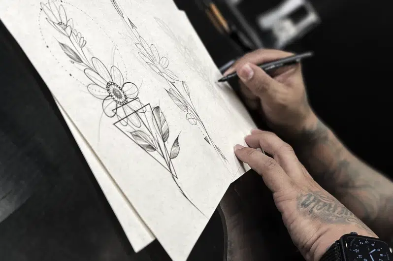 André Cojack segurando uma caneta e fazendo o desenho autoral em um papel